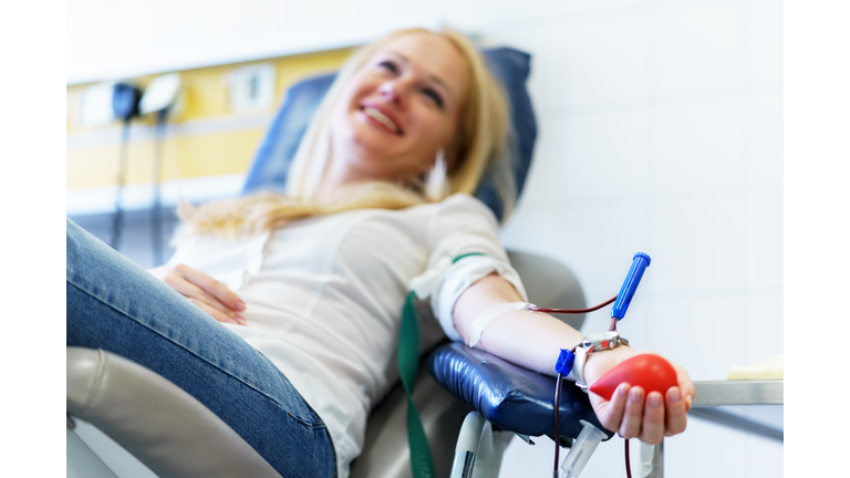 young caucasian woman with toy heart in the hand donates blood for saving lives and medical research