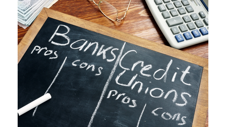 Banks vs. Credit Unions pros and cons written on a blackboard.