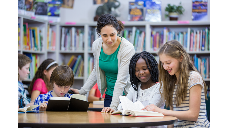 Elementary students working with teacher in library