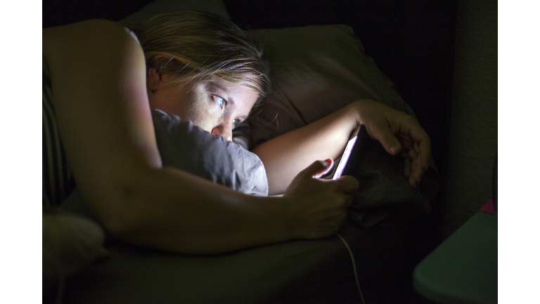 Caucasian woman using cell phone in bed
