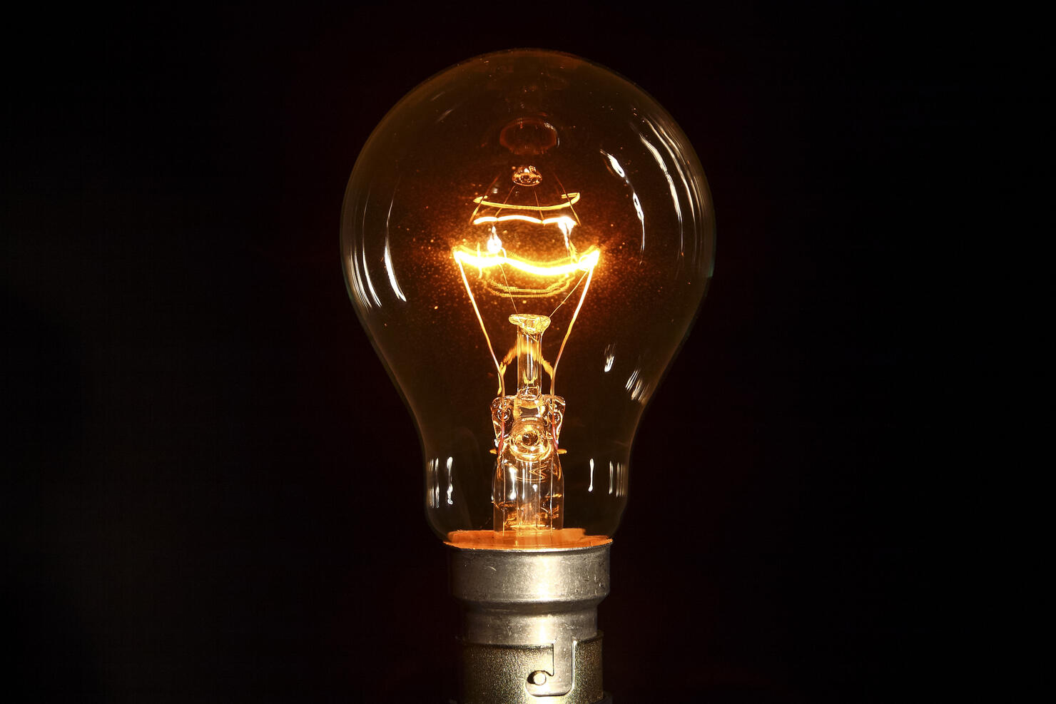 Close-Up Of Illuminated Light Bulb Against Black Background