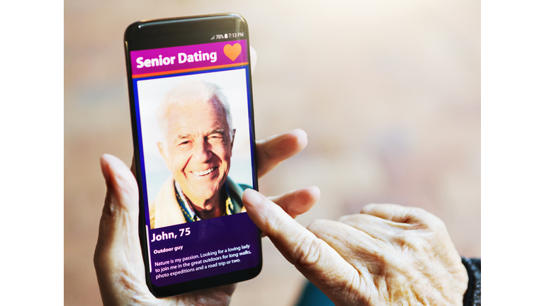 Wrinkled female hand swipes dating app image of handsome man