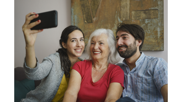 Senior mother taking selfie with daughter and son