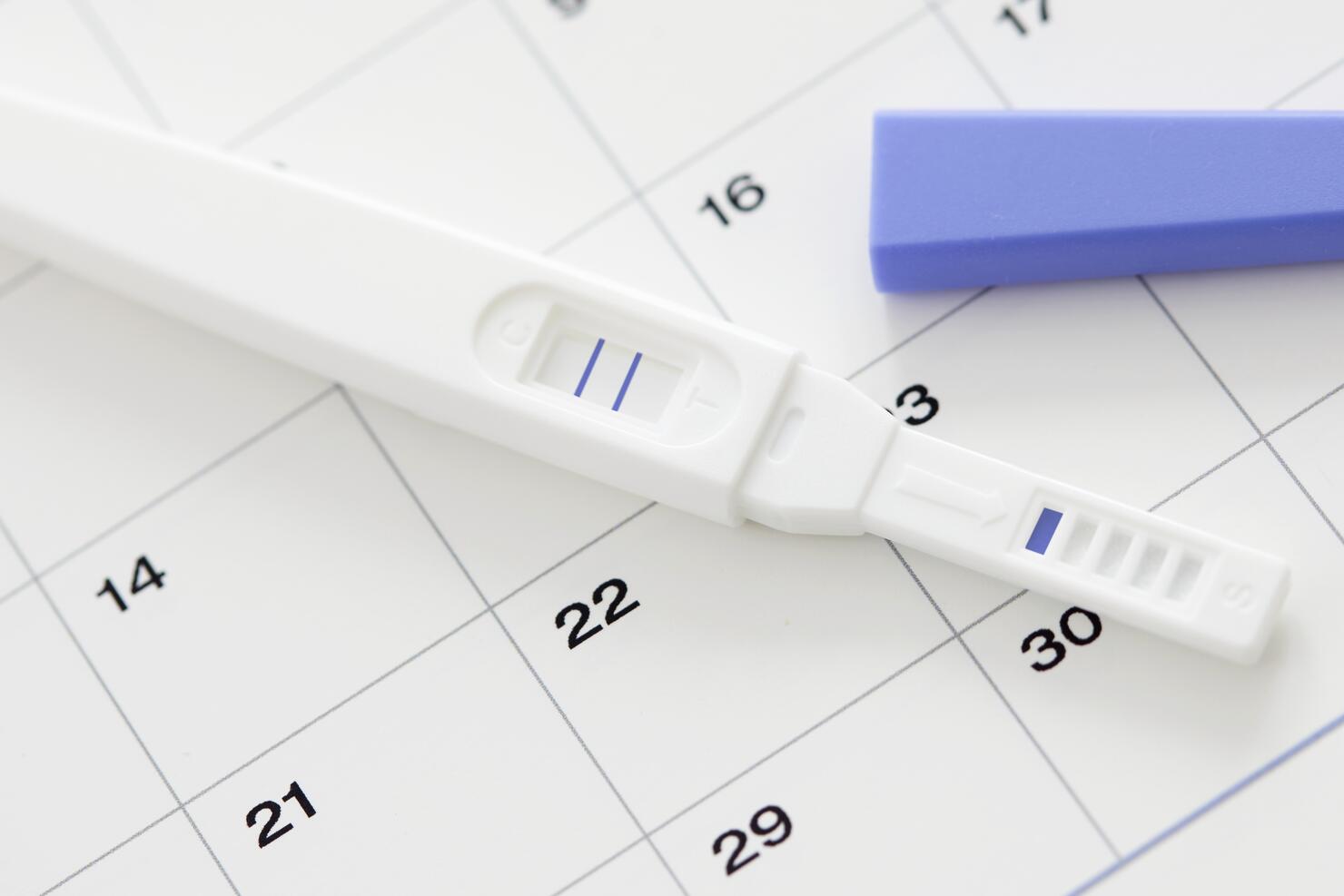 Pregnancy test showing positive result and calendar