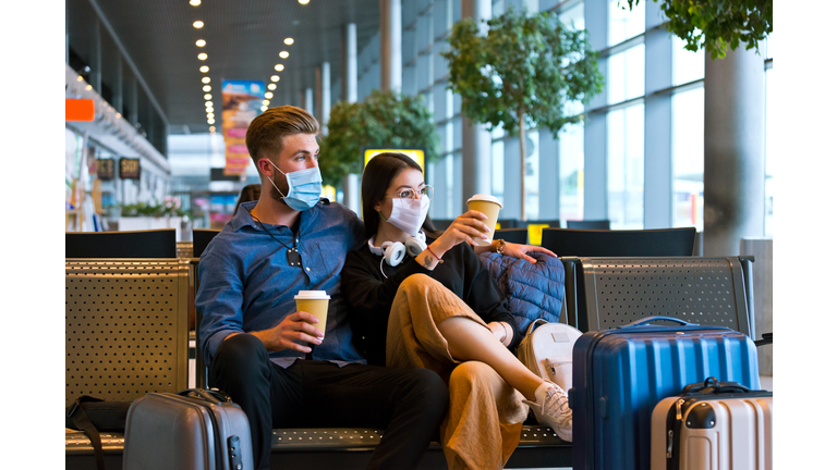 Young couple wearing N95 face masks waiting in airport area