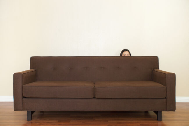 Woman hiding behind sofa