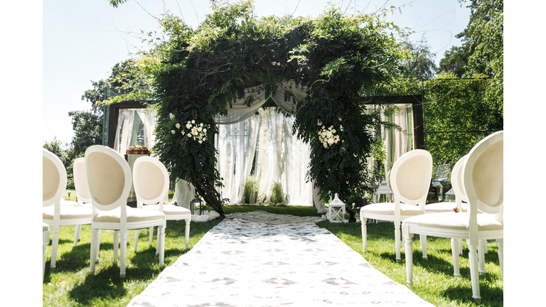 Wedding arch decorated with greenery outdoors - stock photo