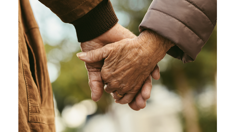 Elderly couple holding hands and walking