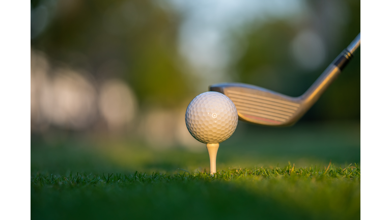 Golf ball on green grass ready to be struck on golf course background