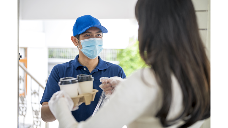 Food Delivery, Takeout Service, Cashless Society. Shot of Courier delivery food and drink to customer in front doorstep.