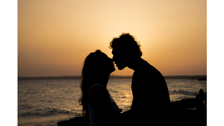 Silhouette of couple kissing at sunset on the beach
