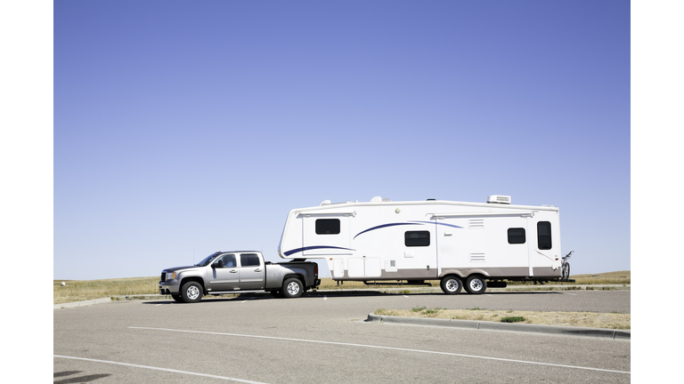 Large white RV trailer hitched to a double cab gray truck