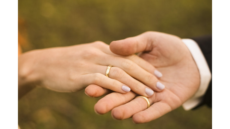 Bridal couple holding hands, showing wedding rings
