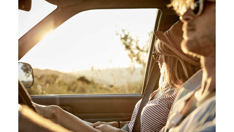 Woman sitting by man driving van during road trip