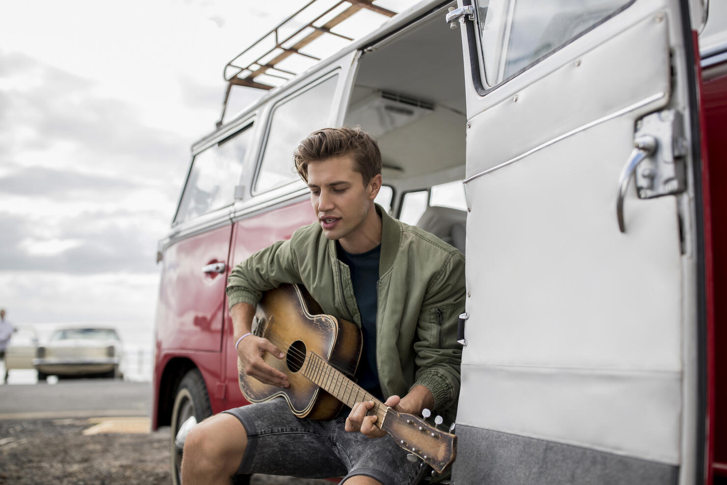 Young man playing guitar at a van