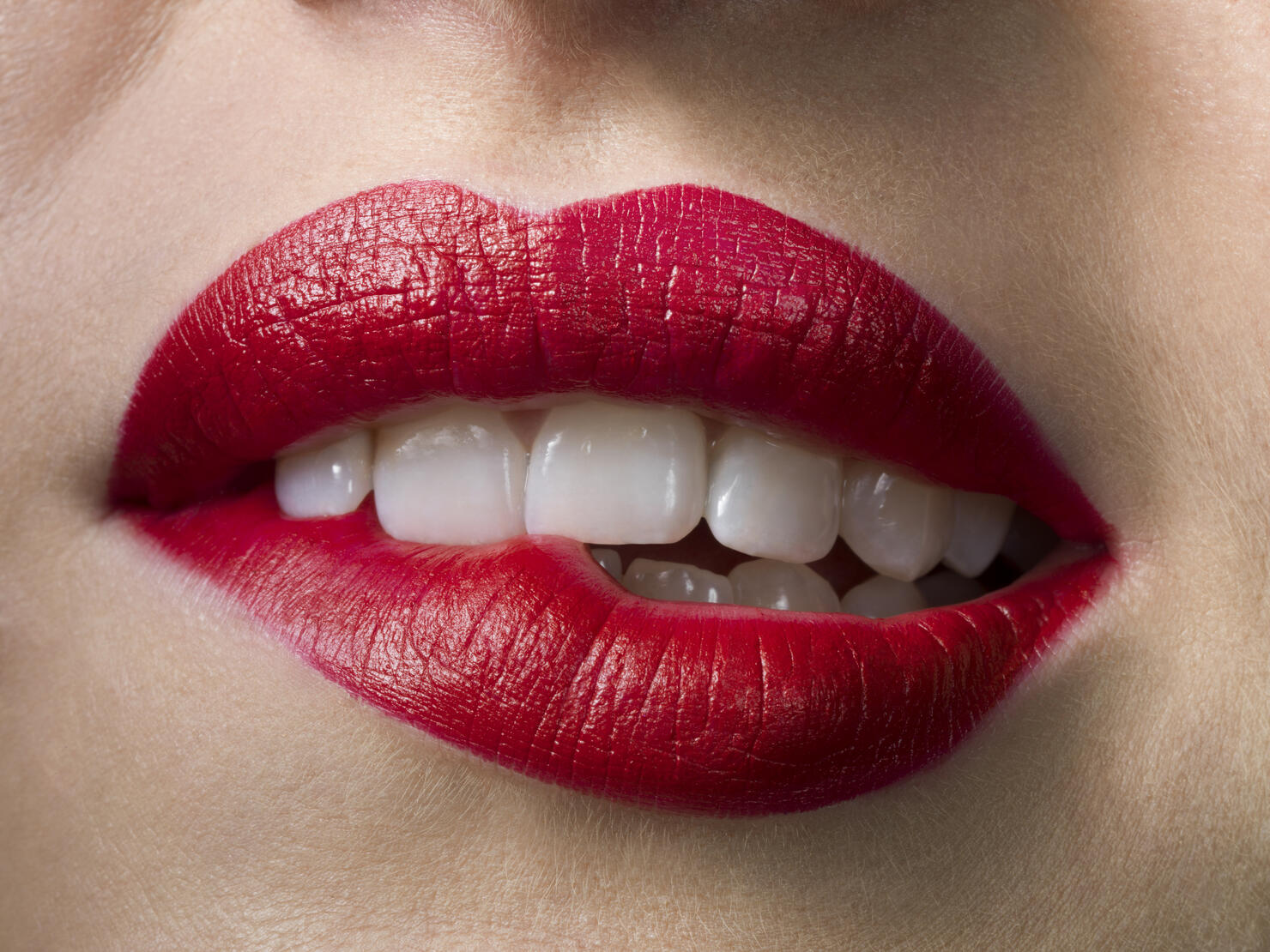 Female with red lipstick, biting lips, close up