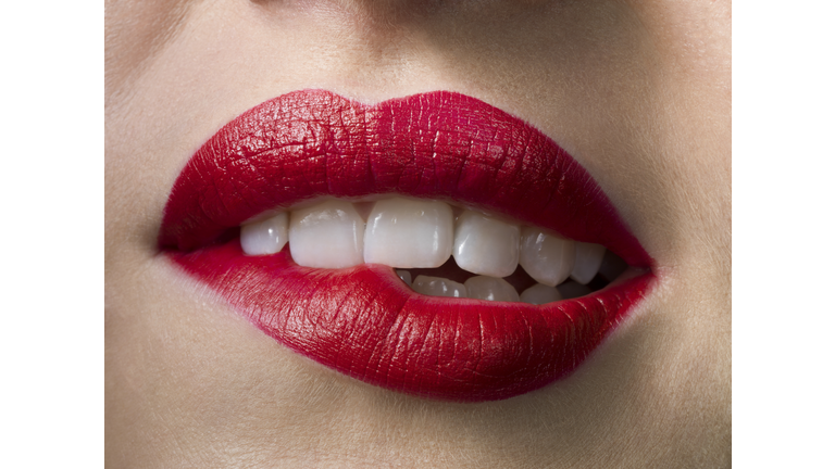 Female with red lipstick, biting lips, close up
