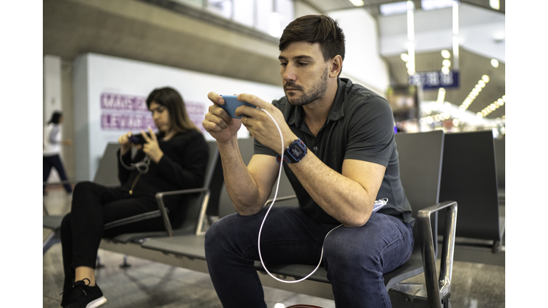 Man using and charging phone at the airport