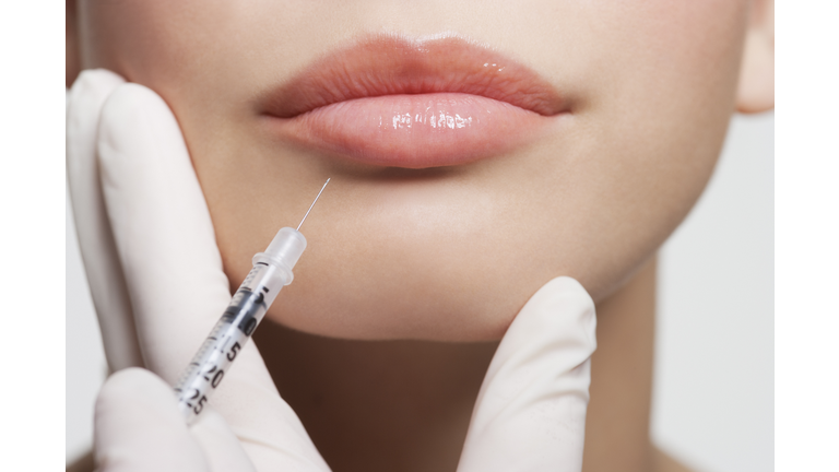 Close up of woman receiving botox injection in lips