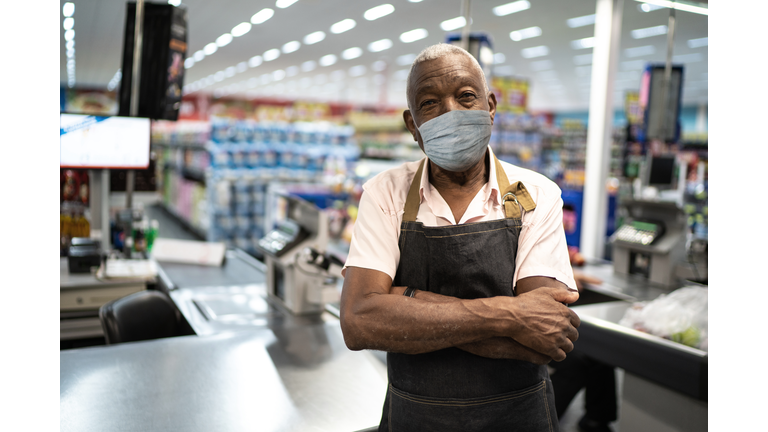 Afro senior man business owner / employee with face mask at supermarket