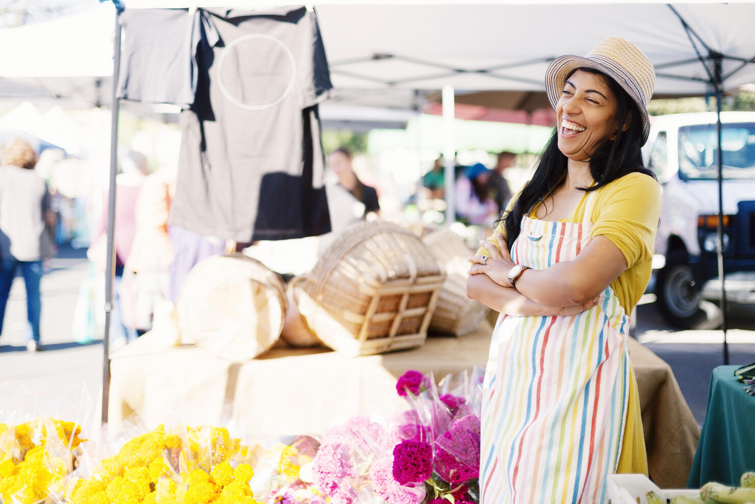 Cheerful vendor with arms crossed standing at farmer's market