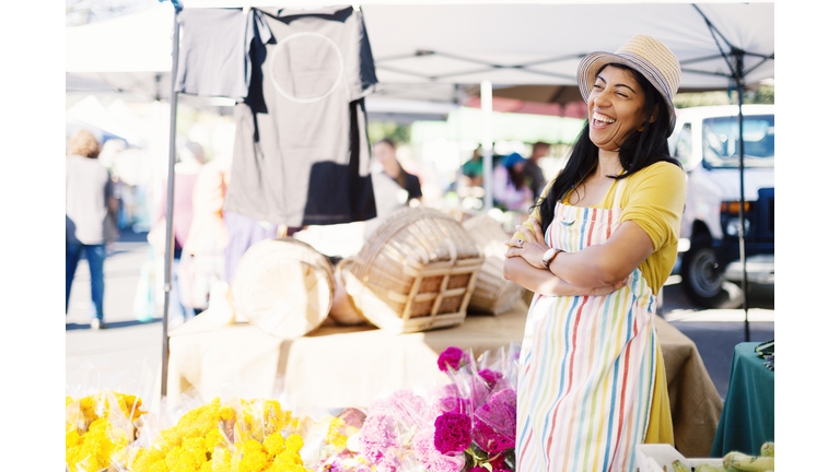 Cheerful vendor with arms crossed standing at farmer's market
