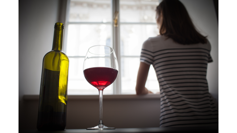 Woman drinking wine alone in the dark room