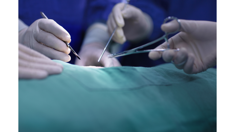 Hands of operating room staff performing surgery