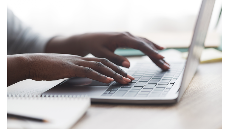 Black woman typing on laptop keyboard while working in office