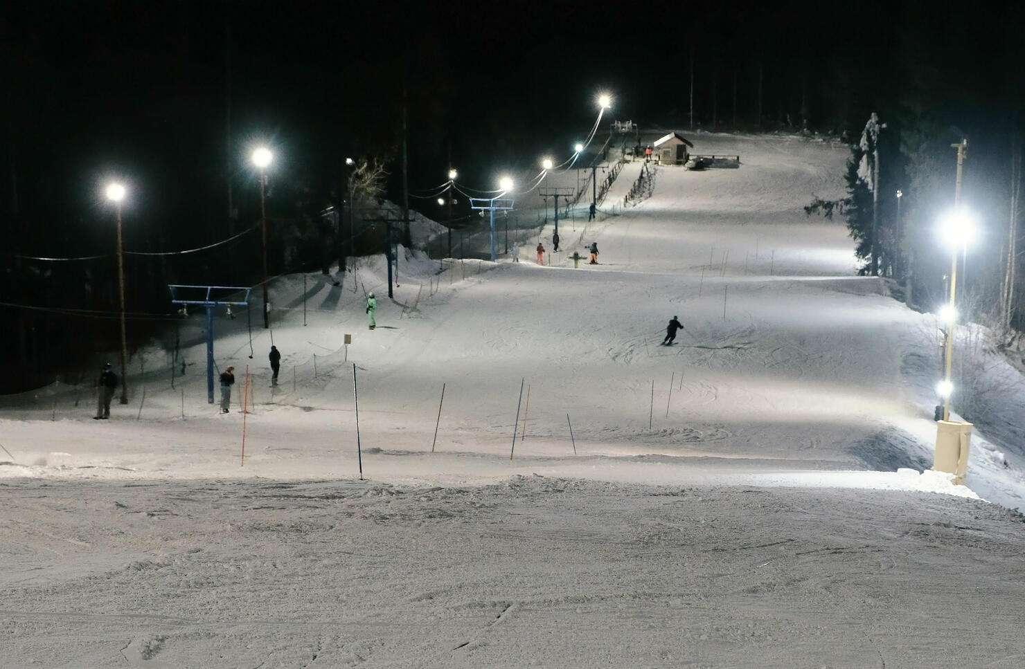 Man goes down the mountain on a mountain skiing slope next to the lift in evening.