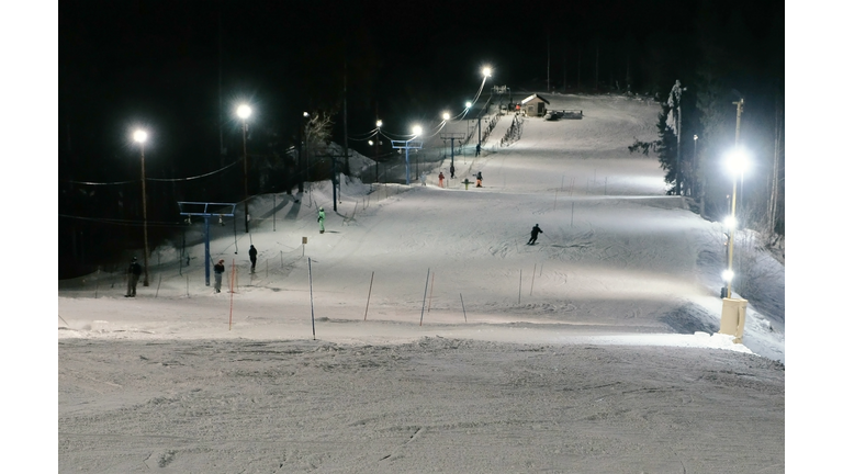 Man goes down the mountain on a mountain skiing slope next to the lift in evening.