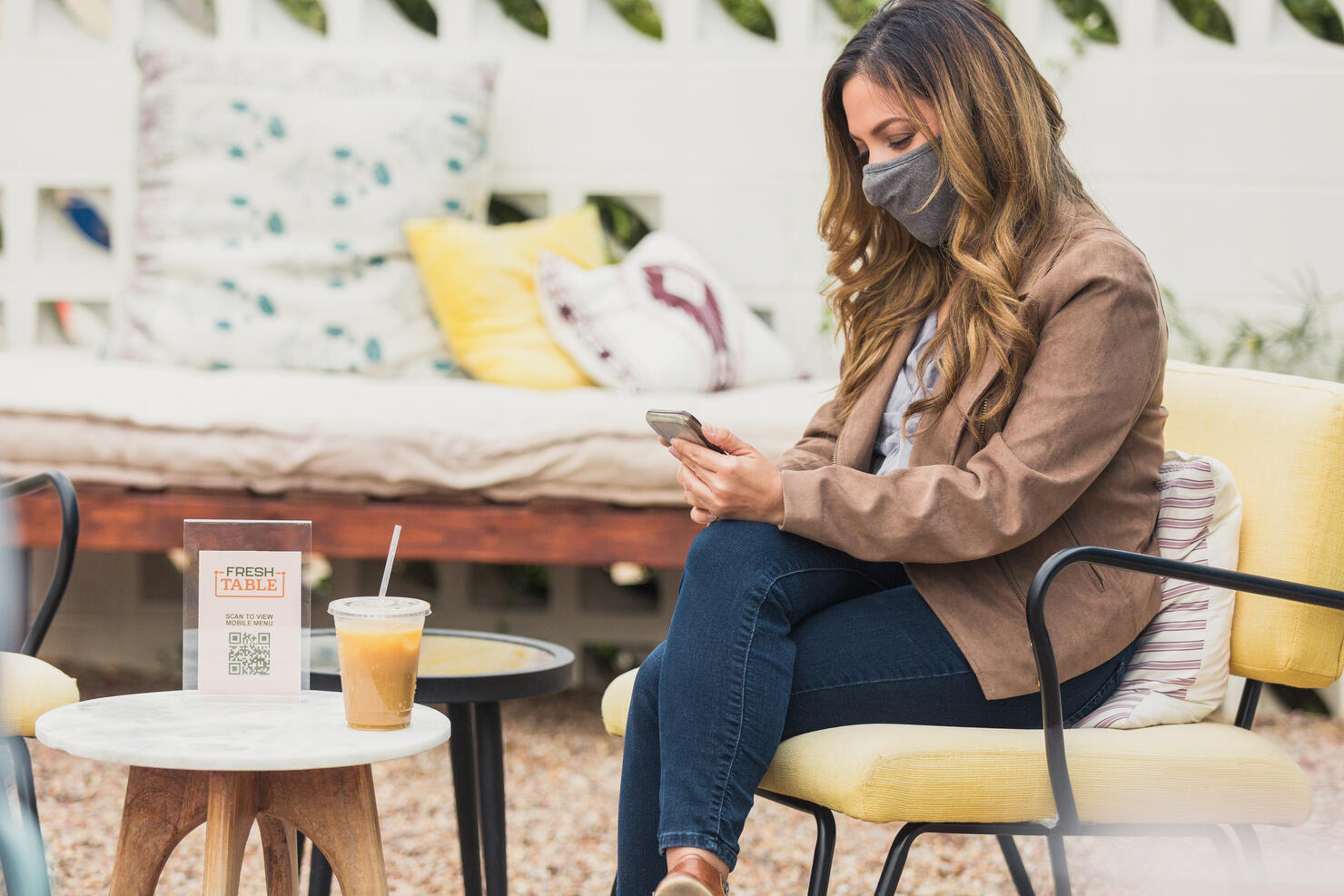 Woman uses phone on coffee shop patior