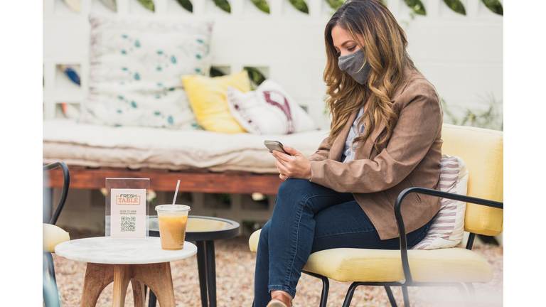 Woman uses phone on coffee shop patior