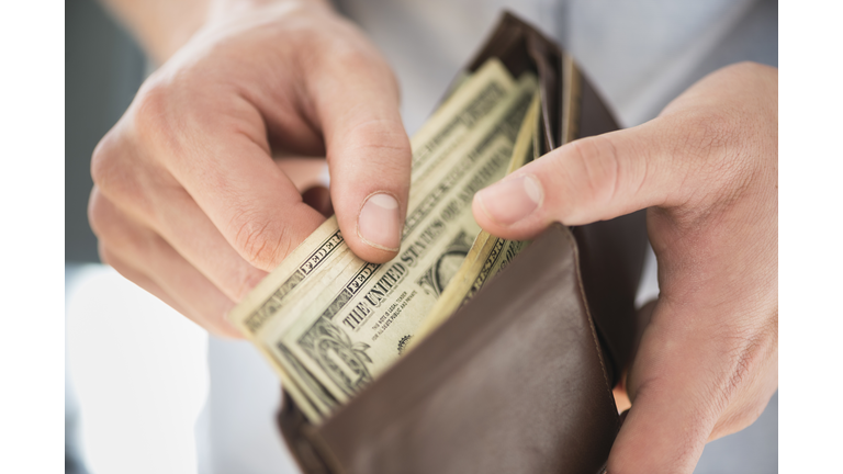 Young man holding wallet and counting money, Jersey City, New Jersey, USA