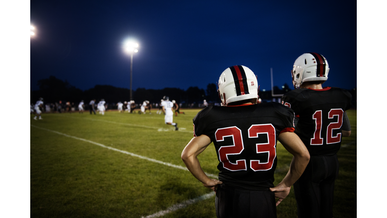 Rear view of American football players standing on Football field