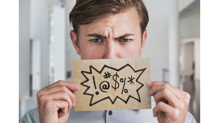 Man holding swear word sign in front of his mouth