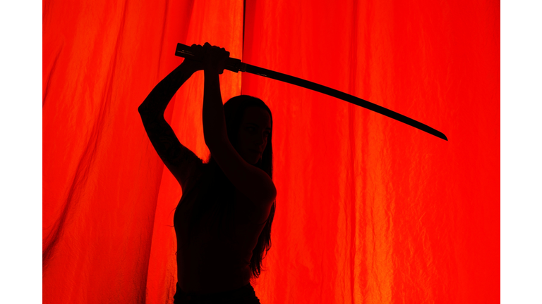 Shadow Of Woman With Sword Seen Through Red Curtain
