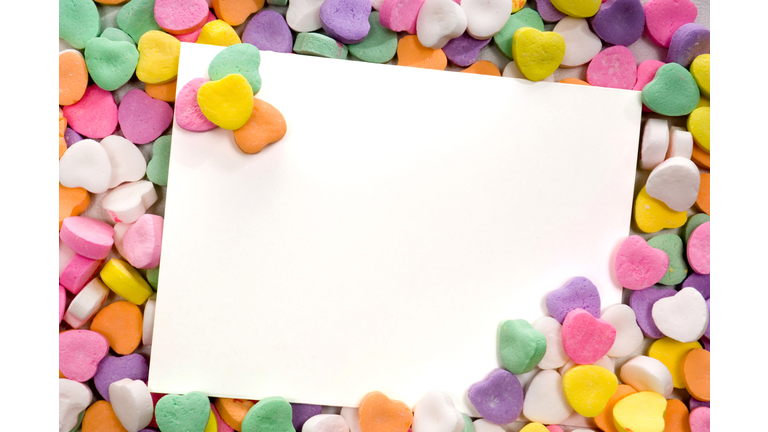 Blank note card surrounded by a pile of candy hearts