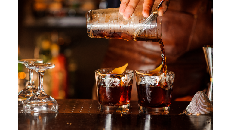 Bartender pouring alcoholic drink into the glasses