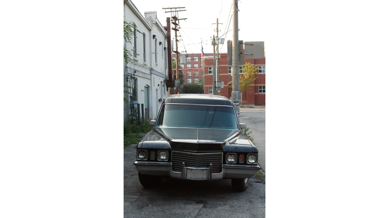 Front View of Black 1972 Cadillac Hearse Parked In Alley