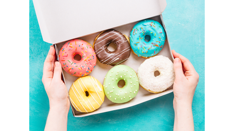 hands holding box with donuts