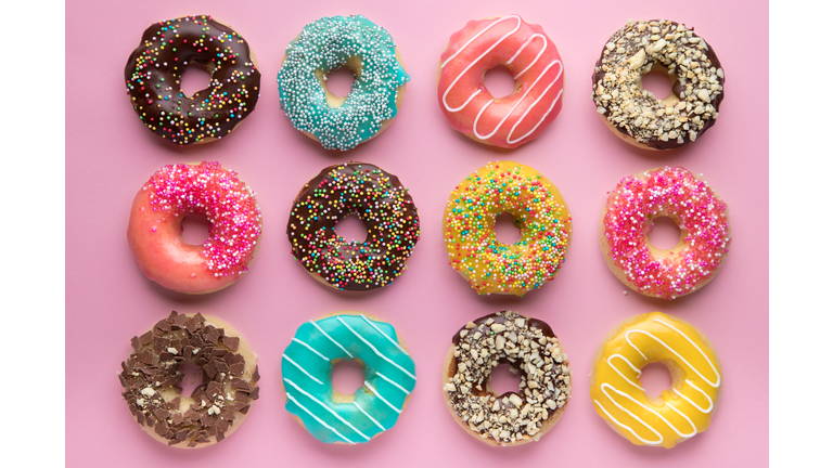 Colorful sweet background. Delicious glazed donuts on pink background.