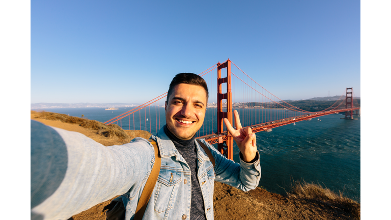 Young smiling happy man taking selfie at Golden Gate Bridge in San Francisco, California, USA