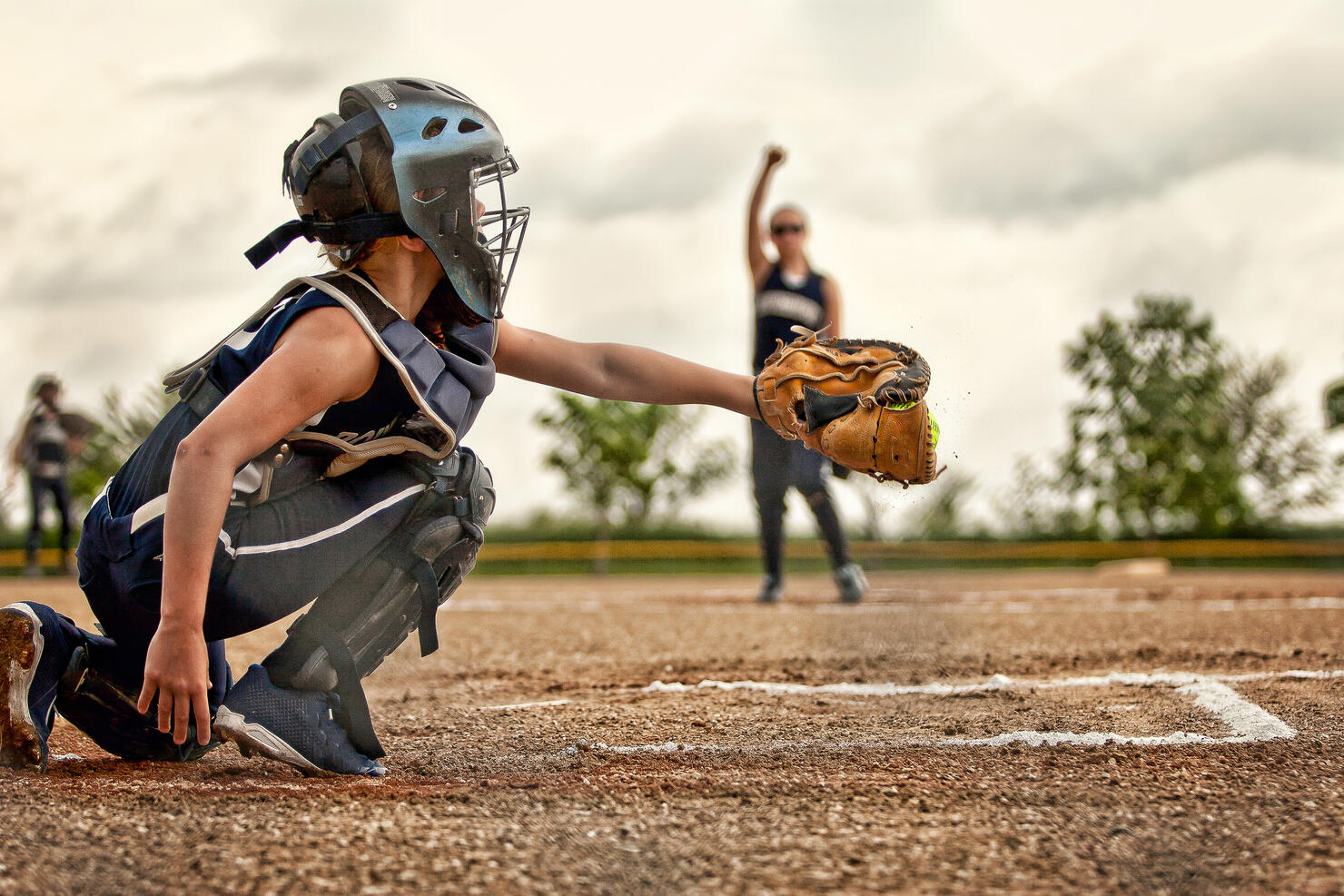 A softball catcher shown catching a pitch