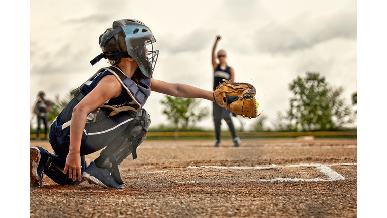 A softball catcher shown catching a pitch