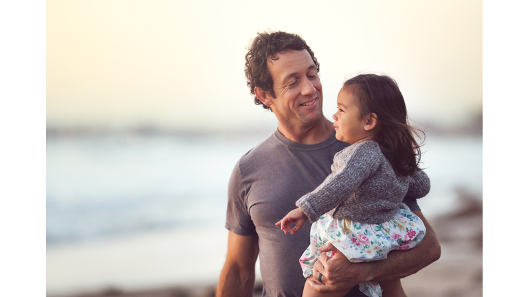 Smiling Dad Holds His Toddler Daughter Outdoors