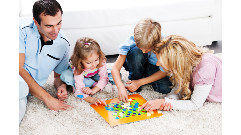 Cheerful parents playing board game with their children.