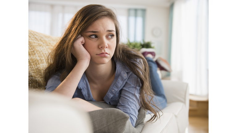 Anxious Hispanic girl laying on sofa