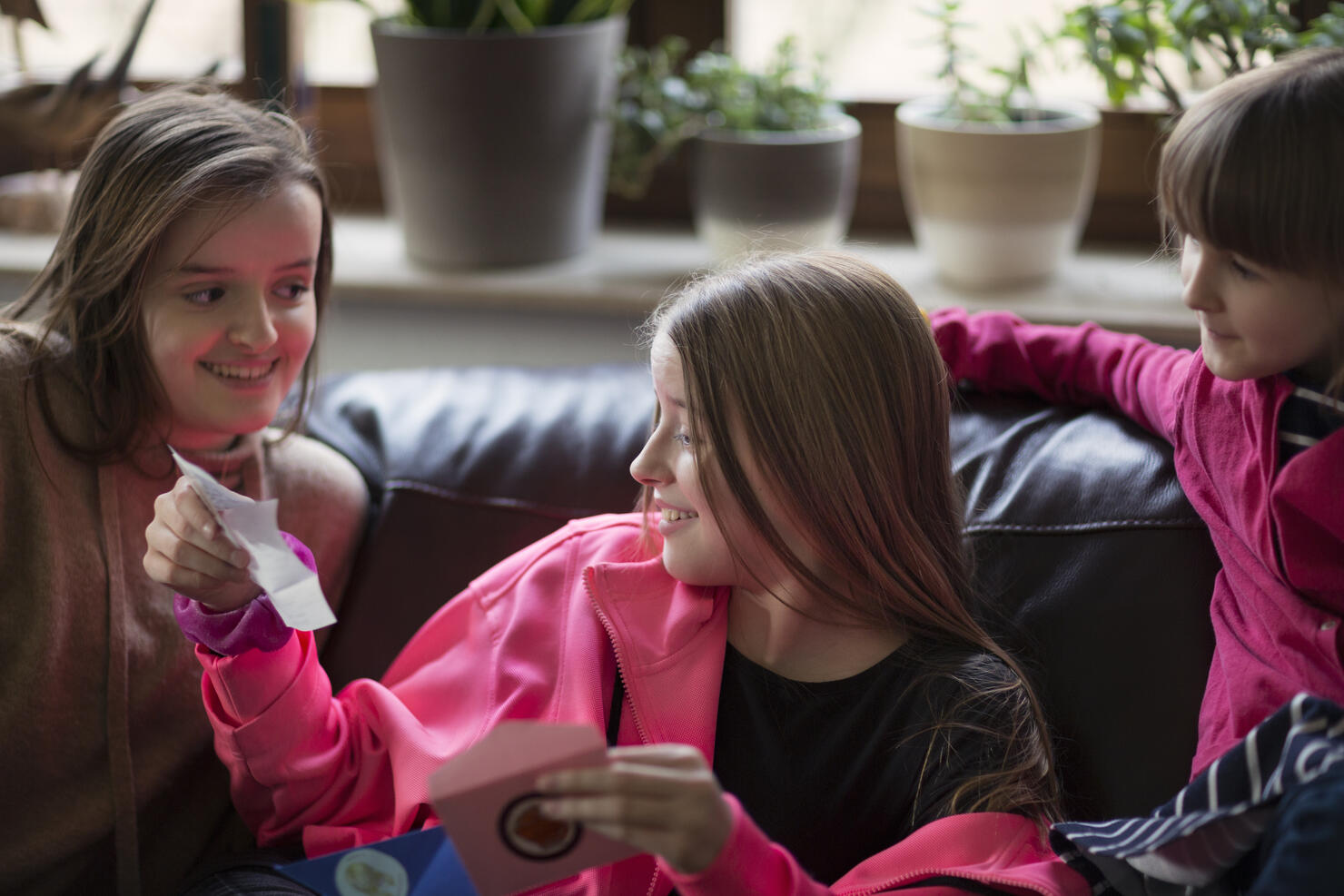 Surprised teenager opening a birthday gift voucher from her two sisters