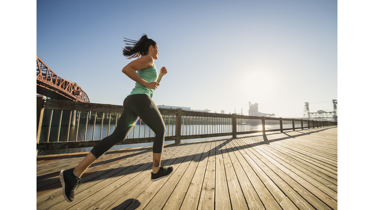 Caucasian woman jogging on urban waterfront